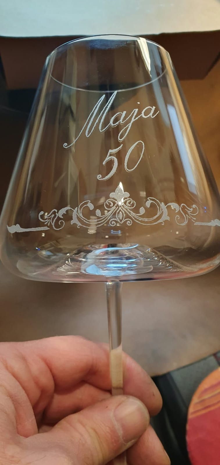 Vinski kozarec z graviranim napisom in okrasnim vencem.