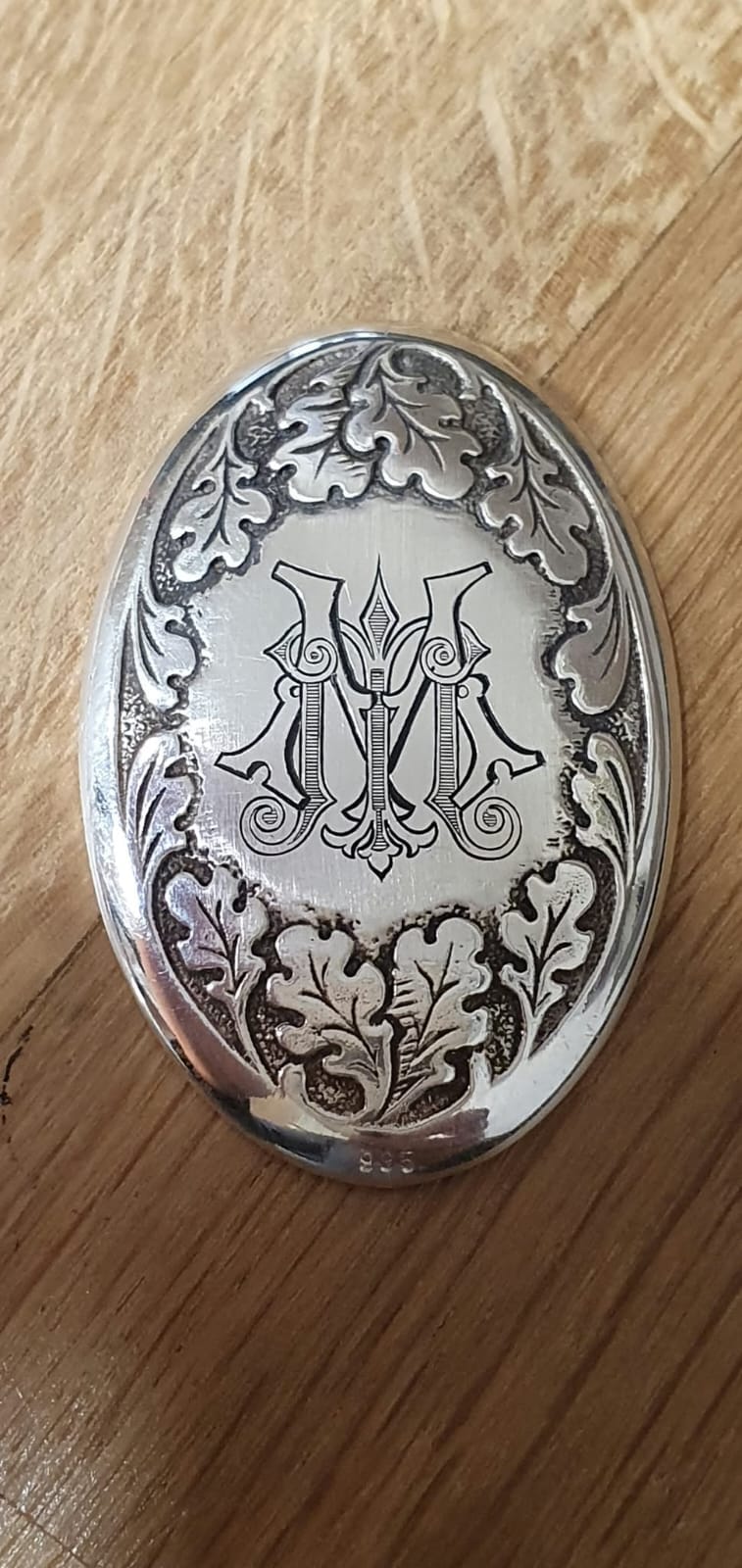 Ovalna srebrna plošča z monogramom, obdanim z reliefom hrastovih listov.
