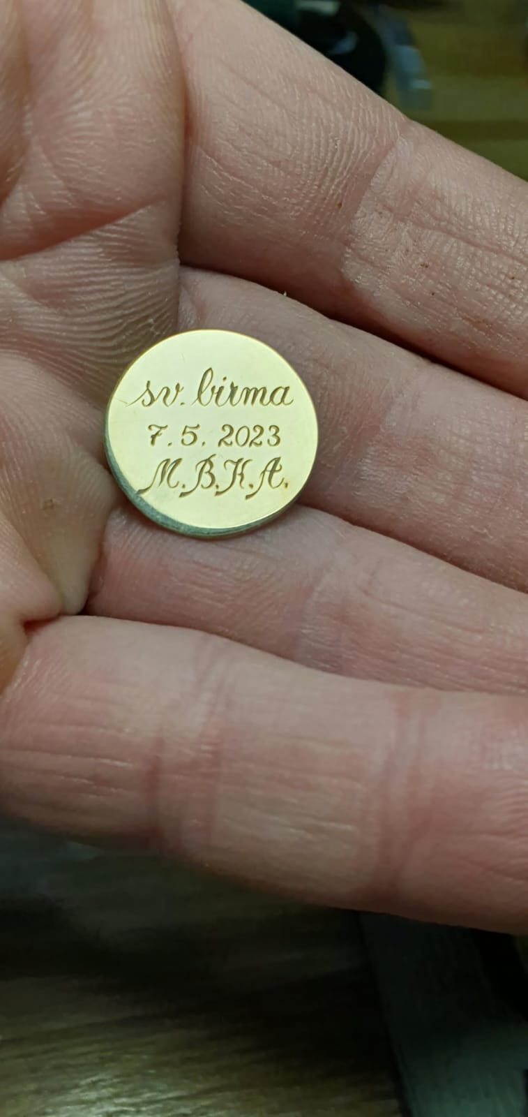 Majhna zlata ploščica z vgraviranim posvetilom.