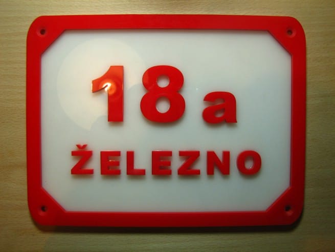 Rdeča tablica s hišno številko in imenom kraja