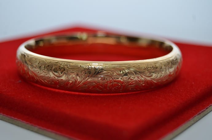 Zlata zapestnica z ročno graviranim cvetličnim ornamentom na rdečem žametu